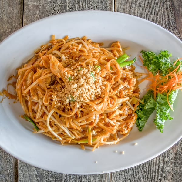 Pad Thai noodles with chicken, bean sprouts, peanuts, and a side of lettuce and carrots.