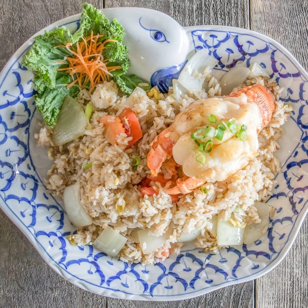 Shrimp fried rice with vegetables and lettuce on a decorative elephant-shaped plate.